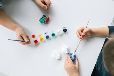 Çocuk alçı figürünü parlak renklerle boyuyor. Çocukların yaratıcılığı kavramı. Anaokulu öğrencisi evde dikiş işi yapıyor..