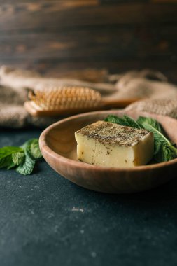 Koyu arkaplanda tahta bir tabakta naneli doğal sabun..