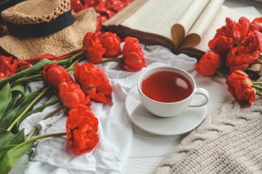 Güzel bahar kompozisyonu, günaydın konsepti. Bir fincan çay, şakayıklar, açık eski kitaplar..