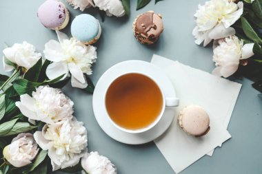 Bir fincan çay, badem kurabiyesi ve şakayık, düz bir manzara. Günaydın konsept.