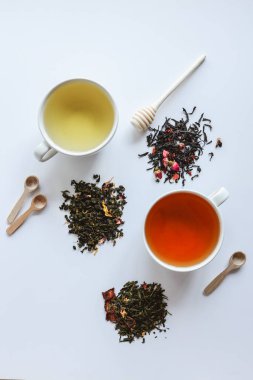 Bitkisel yaprak kurutulmuş çay ve bardaklar, beyaz arka planda üst manzara..