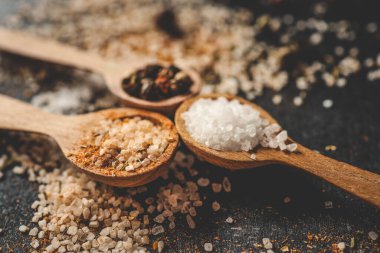 Siyah arka planda farklı baharatlı ahşap kaşıklar, afiş..