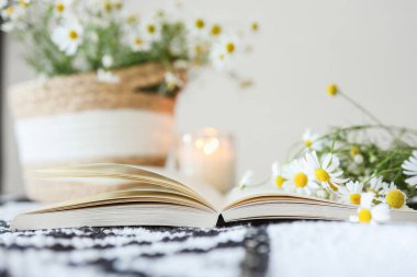 An open book and a bouquet of daisies, atmospheric aesthetic photography.