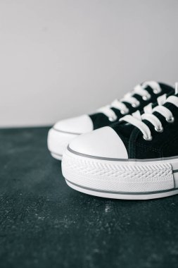 Gri arka planda siyah beyaz spor ayakkabılar.