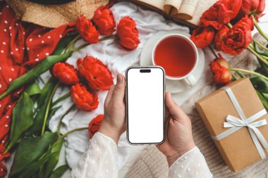 Şenlikli bir arka planda cep telefonu ve bahar çiçeği laleleri. Aşk teması, Anneler Günü, Kadınlar Günü düzlük.
