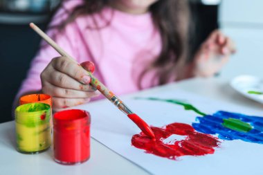 Çocuk boyayla çiçek çizer.