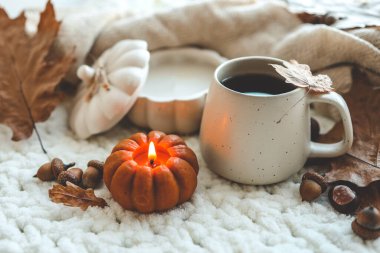 Balkabağı şeklinde yanan mum ve bir fincan çay, sonbahar havası..