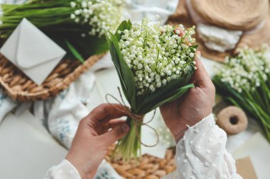 Çiçekçi kız vadideki zambakları elinde tutuyor..