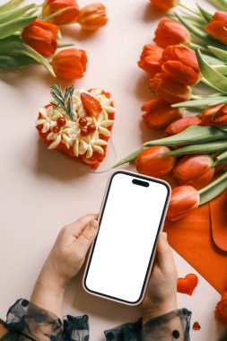 Elinde telefon olan bir kız. Çiçeklerin arka planında izole bir ekran var..