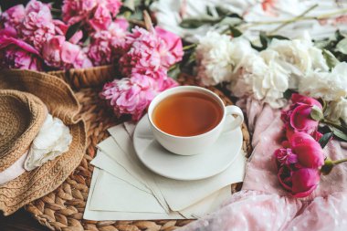Güzel bahar kompozisyonu, günaydın konsepti. Bir fincan çay, şakayık ve açık bir kitap..