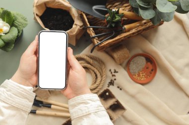 Bahçe araçlarının arkaplanındaki metnin için izole edilmiş bir ekran ile telefon.