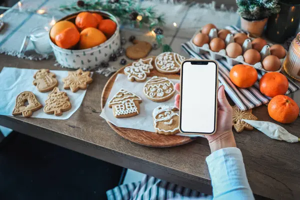 Noel yemeğinin arka planında boş ekranlı bir telefon. Mesaj için yer. Ana sınıf davetiyesi. Mutlu Noeller.