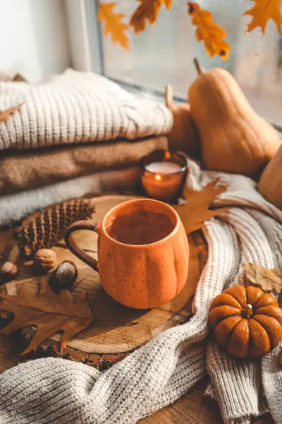 Pencere kenarında güz yaprakları, balkabakları ve baharatlarla kaynayan bir fincan çay. Sonbahar havası