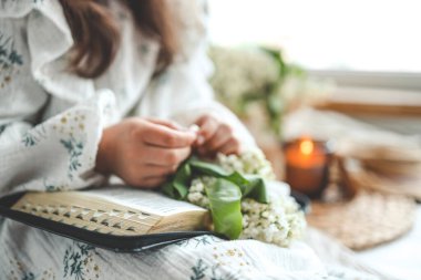 İncil okuyan kız, açık kitap ve leylak dalı, samimi bir fotoğraf..