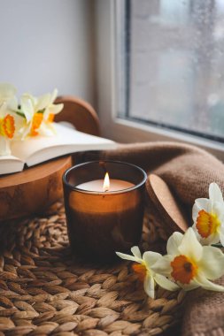 Pencerenin kenarında mum ve nergis, bahar kompozisyonu.