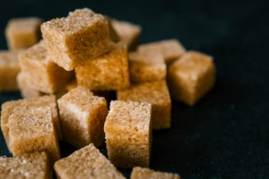 Siyah arkaplanda kamış şekeri küpleri.