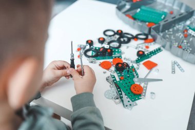 Elinde tornavidayla küçük bir çocuk bir metal yapımcısıyla oynuyor..