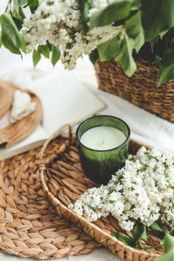 Yeşil bir kavanozda mum, açık bir kitap ve bir buket beyaz leylak, bahar içleri..
