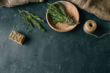 Solid shampoo with rosemary in a wooden plate on a dark background.