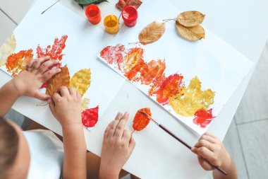 Children color the leaves and make a print, autumn creativity. clipart