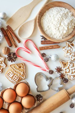 Pastanenin arka planında Noel pişirmek için malzemeler var. Masanın üstünde un, yumurta, tarçın ve zencefilli ekmek..
