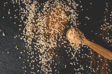 Tahta kaşık, deniz tuzu ve baharatlı siyah arka plan..