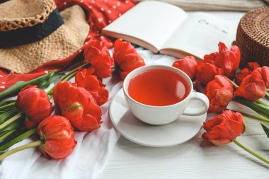 Güzel bahar kompozisyonu, günaydın konsepti. Bir fincan çay, şakayık, açık kitap..