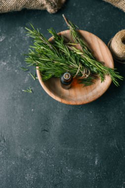 Esans taze biberiye dallar üzerinde karanlık bir arka plan ile bir şişe.