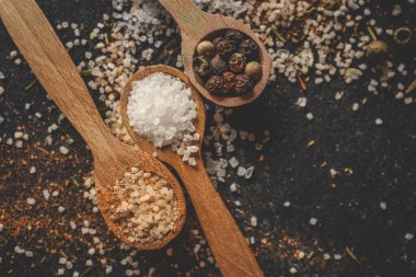 Siyah arka planda farklı baharatlı ahşap kaşıklar, afiş..