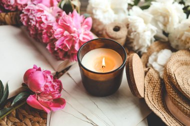 Sıcak bahar kompozisyonu, yanan mum, şakayıklar ve şapka..