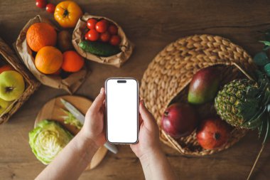 Mutfağın arka planında izole bir ekran bulunan telefon, kalori sayma konsepti ve uygun beslenme.