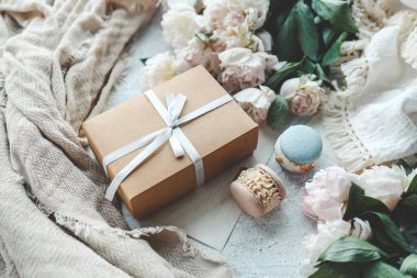 Fiyonklu hediye kutusu, beyaz şakayıklar ve tatlı kurabiyeler, tatil konsepti..