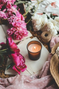 Sıcak bahar kompozisyonu, yanan mum, şakayıklar ve şapka..