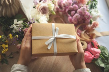 Evde çiçeklerle birlikte hediye kutusu ellerinde..