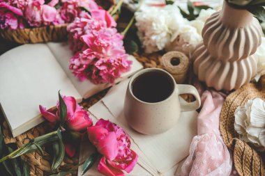 Güzel bahar kompozisyonu, günaydın konsepti. Bir fincan çay, şakayık ve açık bir kitap..