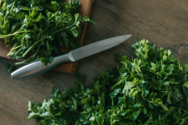 Bambu kesme tahtasında doğranmış taze bitkiler: Bir yığın doğranmış nane, kişniş ve ağaç kesme tahtasında maydanoz.