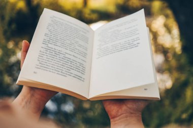 Günbatımı arka planında açık bir kitap. Okuma, çalışma, okul. Açık havada bir kitap oku..