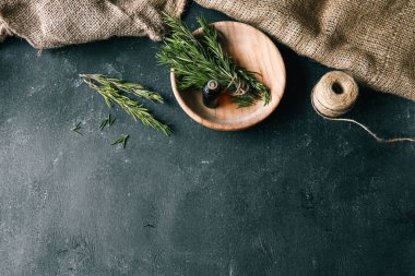 Esans taze biberiye dallar üzerinde karanlık bir arka plan ile bir şişe.