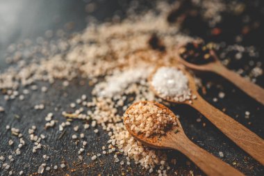 Siyah arka planda farklı baharatlı ahşap kaşıklar, afiş..