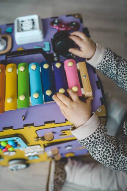 Yoğun yönetim kurulu. Bir çocuk, evinde güzel motor becerileri geliştirmek için tasarlanmış oyuncak bir modelle zevkle oynar..