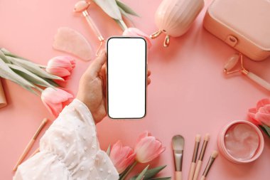 Kozmetik ürünlerinin arka planında izole bir ekran olan telefon ellerinizde, metinleriniz için bir yer.