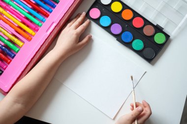 Küçük kız boş bir kağıt üzerine resim yapmaya hazırlanıyor. Çocuk çizimi. Yukarıdan görüntüle.