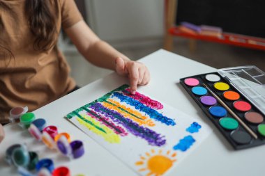 Çocuk çiçek çizer. Parmak boyalarıyla çizim yapmak için fikirler. Beyaz arka plandaki çocuklar için parmak boyama. Parmak boyasıyla resim yapan küçük bir kız. Çocuk gelişimi kavramı.