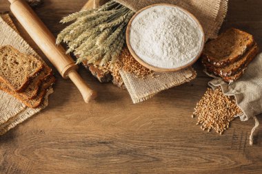 Ekmek, tahıl, buğday ve un başakları ahşap bir arka planda, fırın reklam afişi