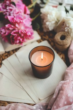 Sıcak bahar kompozisyonu, yanan mum, şakayıklar ve şapka..