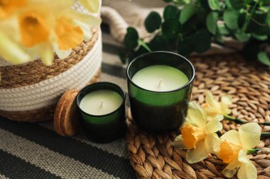 İki mum ve içinde nergis olan bir sepet..