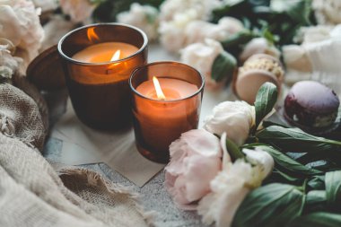 Sıcak bir evde yanan iki mum, beyaz şakayıklar ve badem kurabiyeleri..