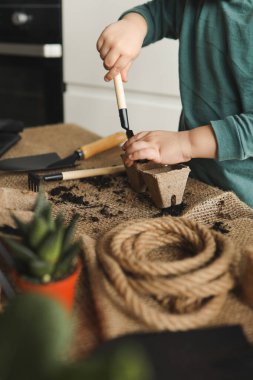 Küçük çocuk bahçeyle uğraşıyor..