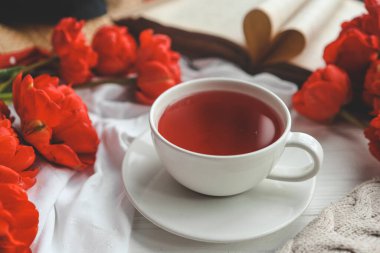 Güzel bahar kompozisyonu, günaydın konsepti. Bir fincan çay, şakayıklar, açık eski kitaplar..