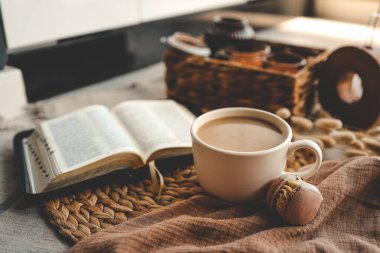 Bir fincan kahve ve badem kurabiyesi, sıcak ev içinde açık İncil, günaydın konsepti..